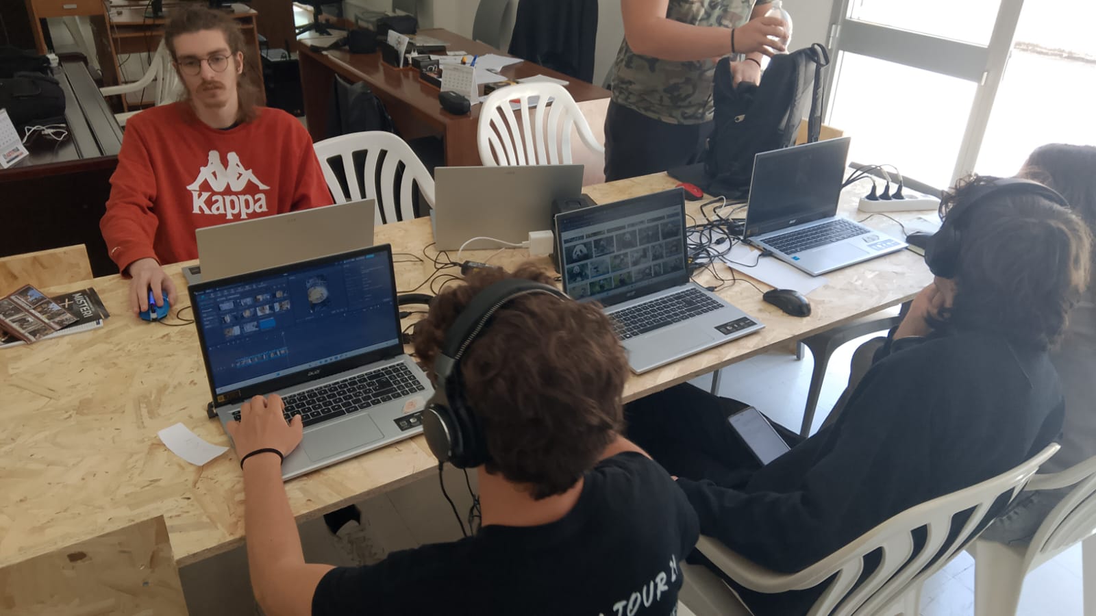 Gruppo di studenti in PCTO lavorano al computer su progetti di montaggio video e grafica presso il centro studi tiformiamonoi.it a Trapani, in un clima di collaborazione e supporto emotivo.